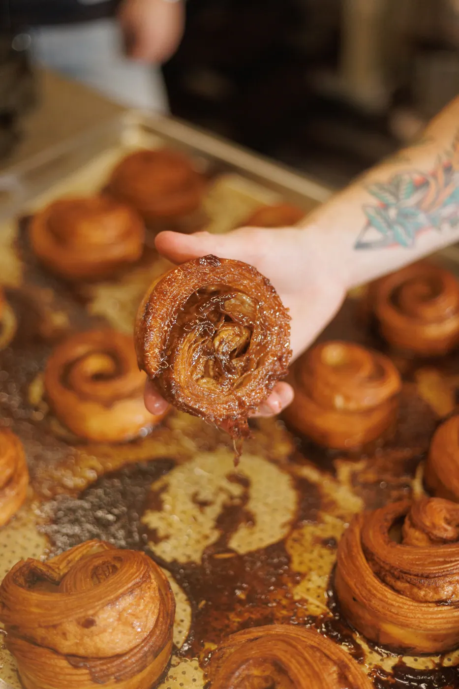 Mão segurando um cinnamon roll recém-assado