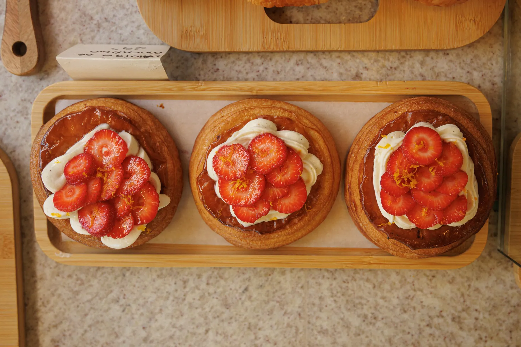 Três danishes de morango em bandeja de madeira