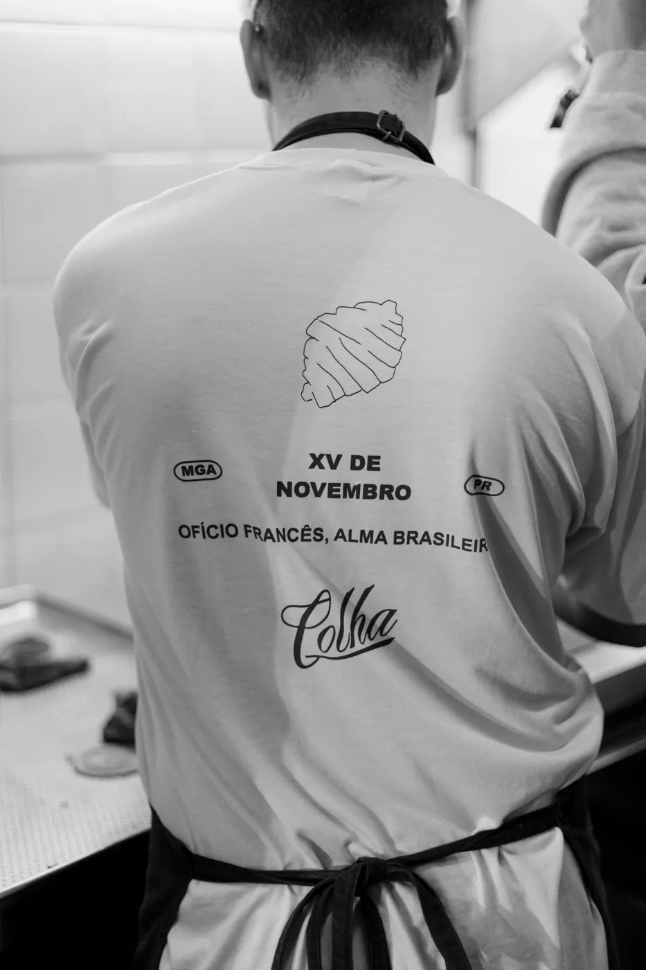 Padeiro de costas com camiseta da Colha: Ofício francês, alma brasileira