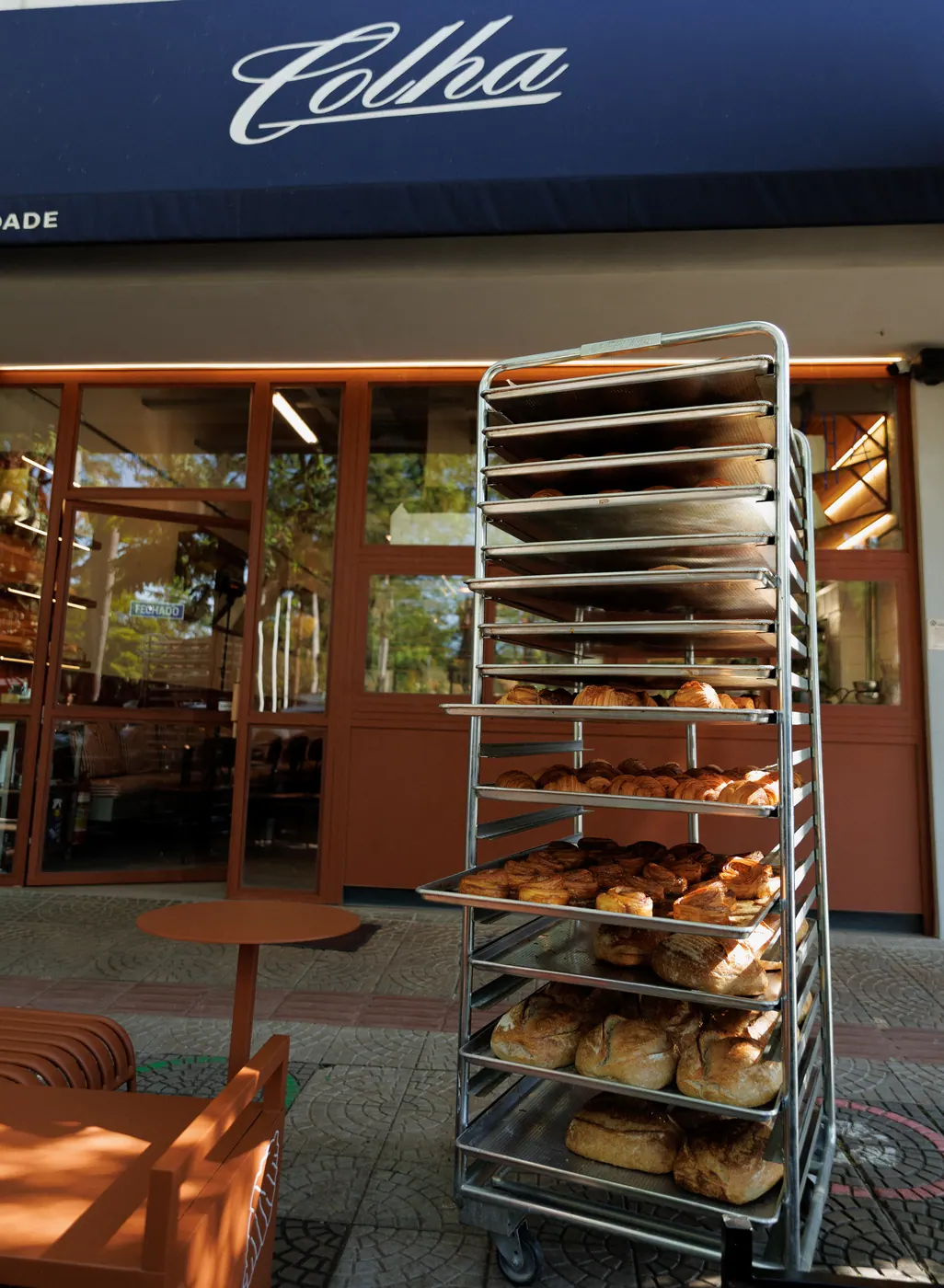 Fachada da Colha Padaria da Cidade em Maringá com carrinho de bandejas de viennoiseries na calçada