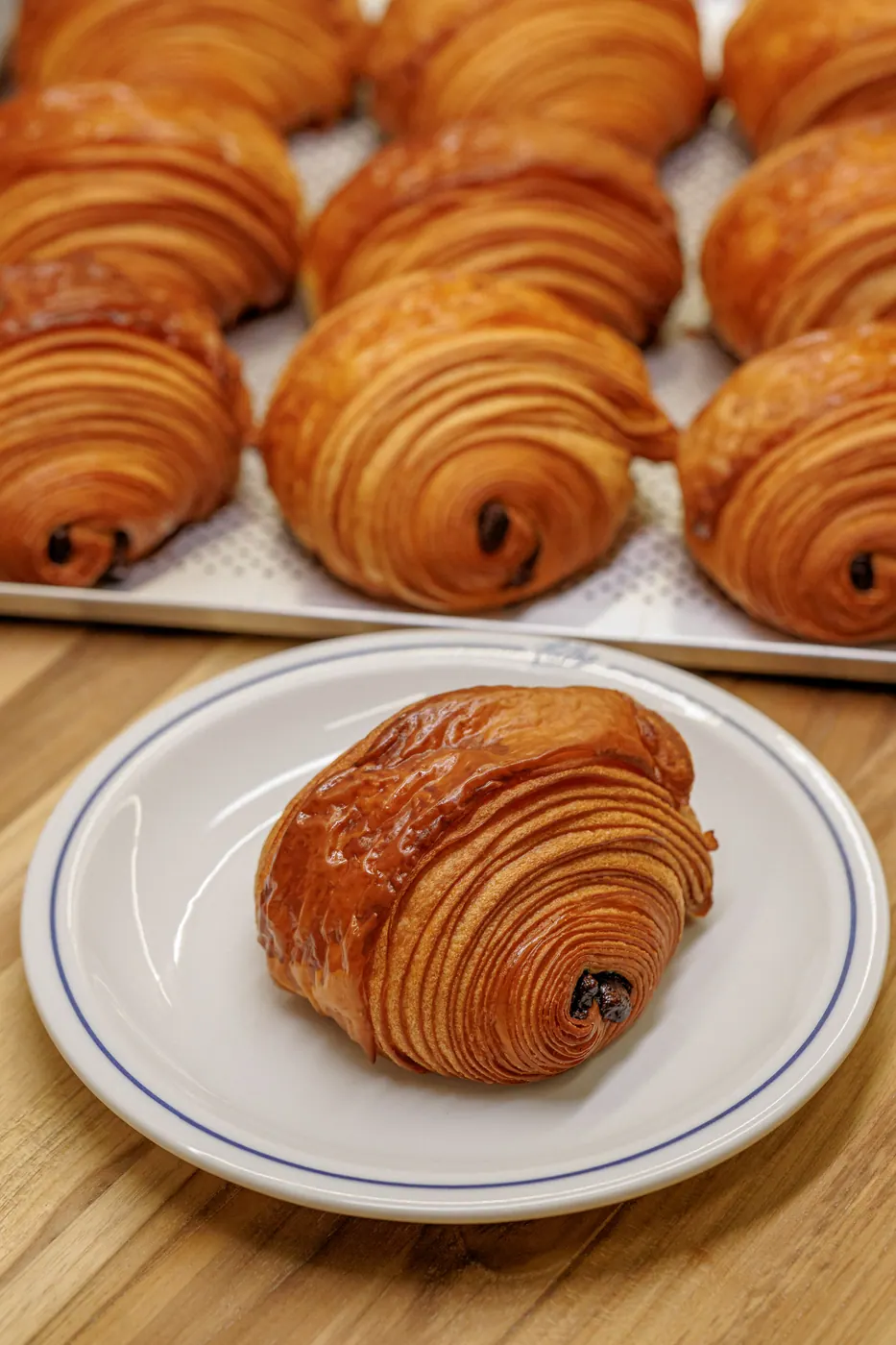 Pain au chocolat em prato da Colha sobre mesa de madeira