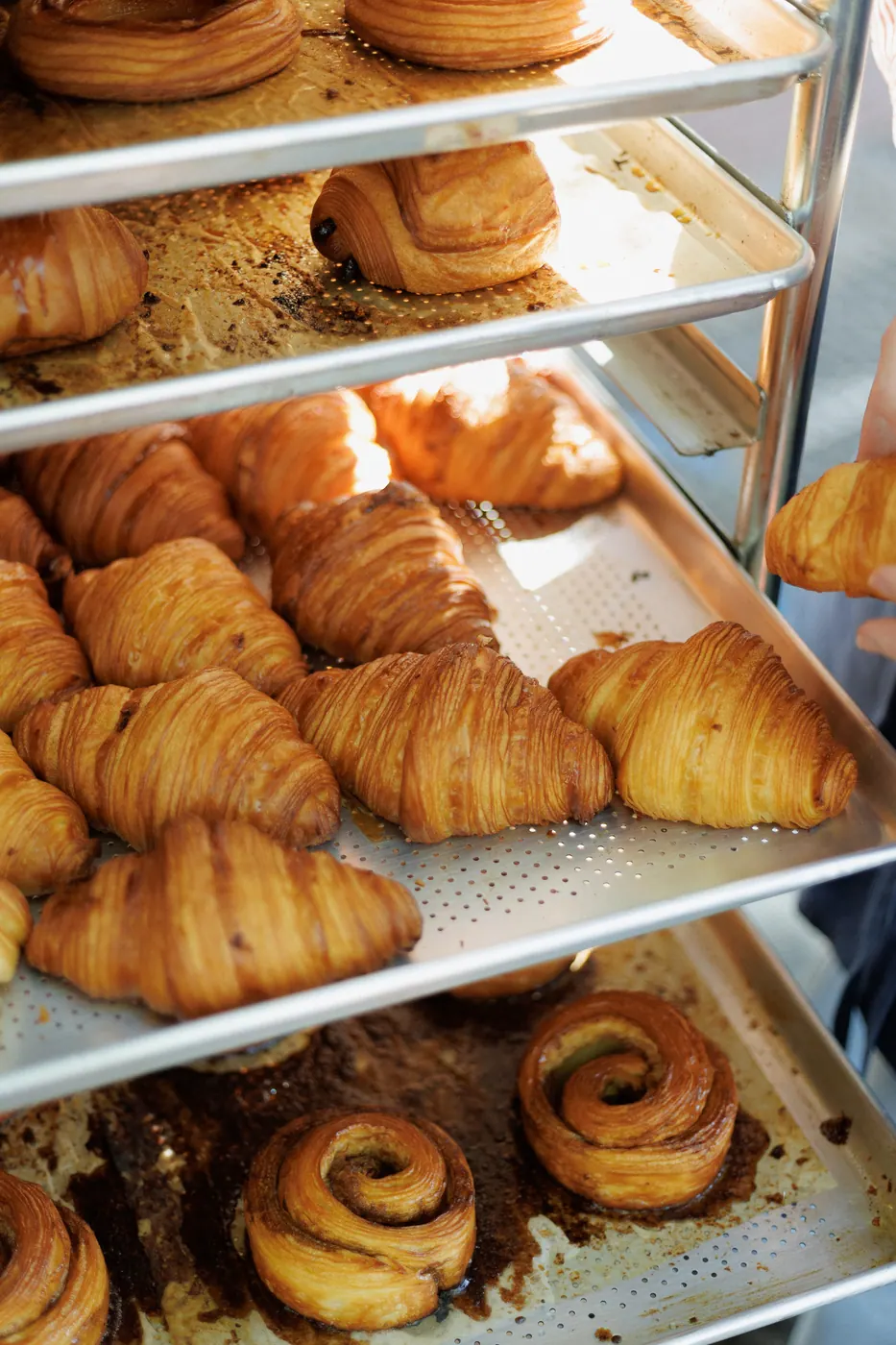 Bandejas de croissants e cinnamon rolls recém-assados no carrinho da padaria