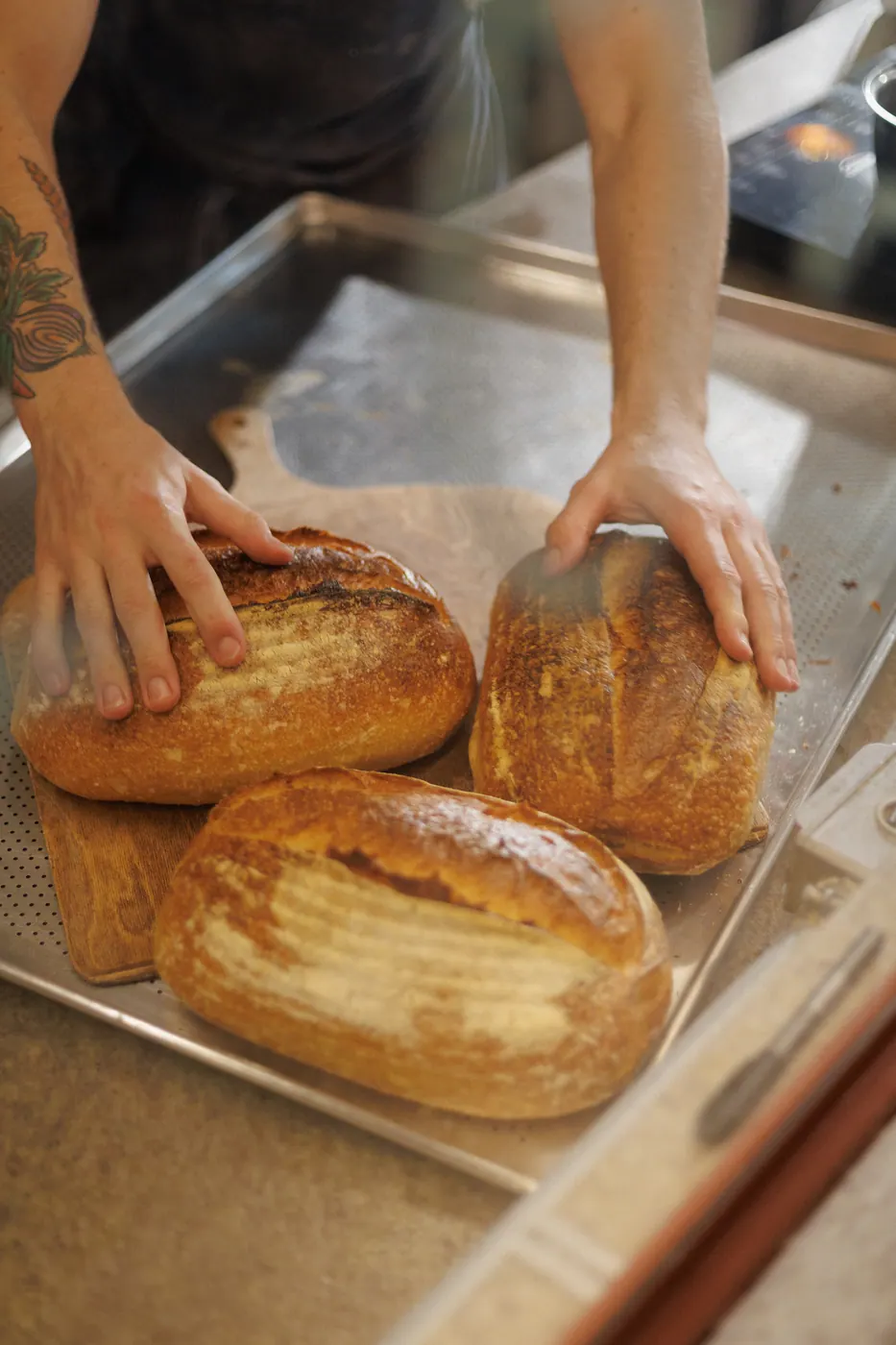 Mãos organizando pães sourdough recém-assados