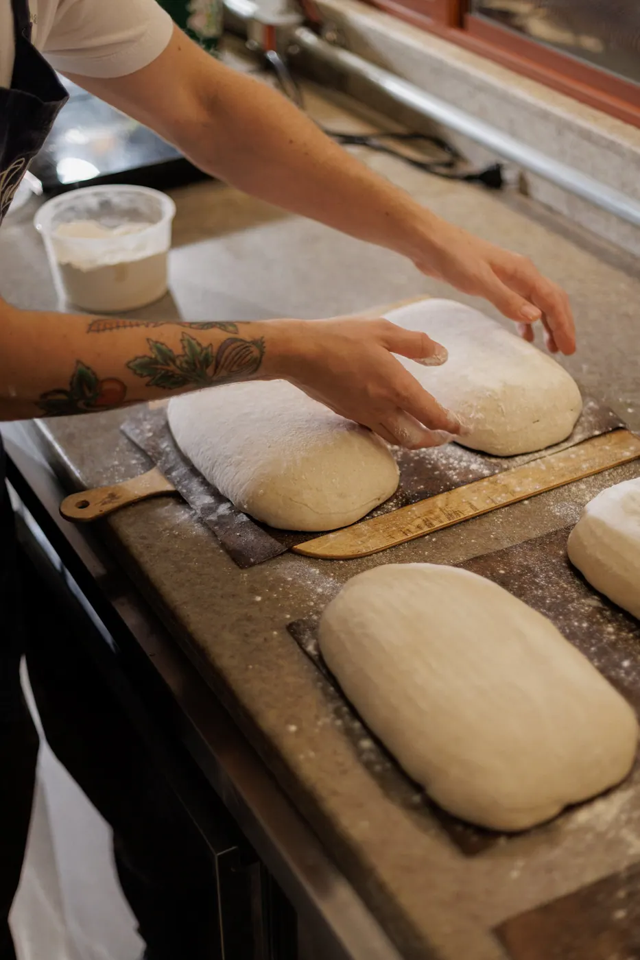 Padeiro moldando a massa do pão sourdough na bancada