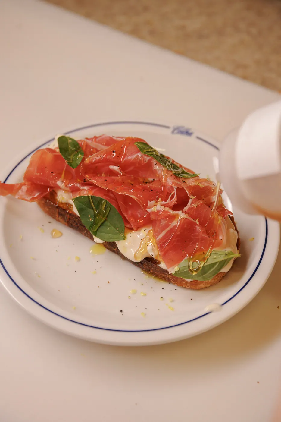 Tartine de parma e stracciatella sendo finalizada com mel
